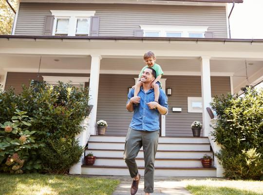 father and son in front of house